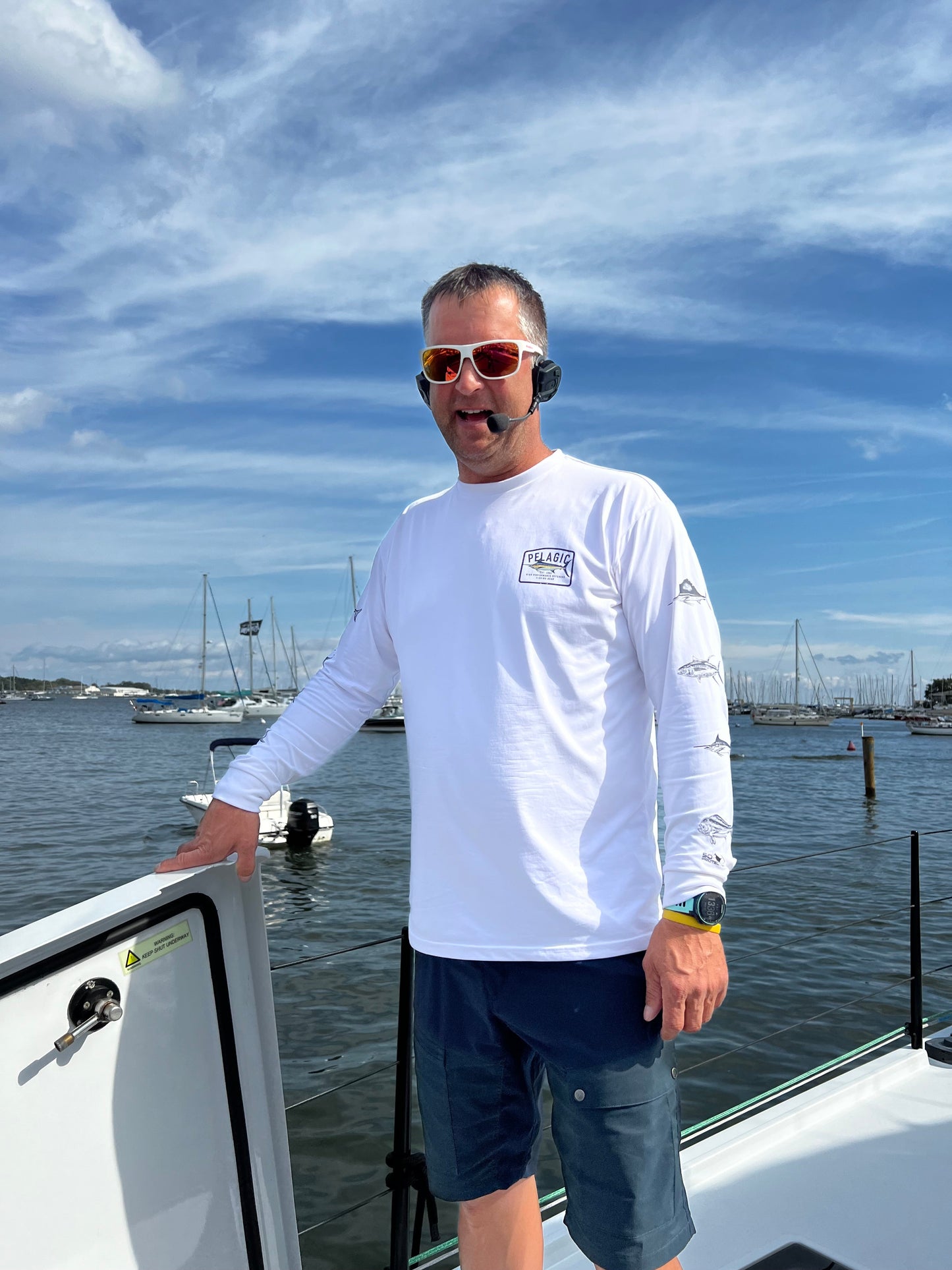 Boater wearing a bluetooth headset also known as a mariage savers. He is talking to someone else on the boat giving instructions.